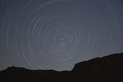 night sky Concentric circles created by stars moving through the night sky over a silhouetted rock face universe